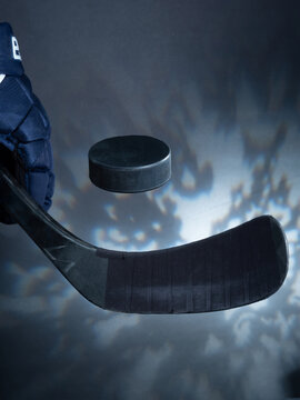 Closeup of a black ice hockey stick shooting a puck against a dreamy background.