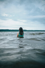 Chica bañándose en el lago de espaldas a la cámara.