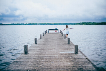Dos niñas jugando en un embarcadero frente a las aguas de un lago.