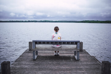 Chica sentada a solas en un embarcadero.