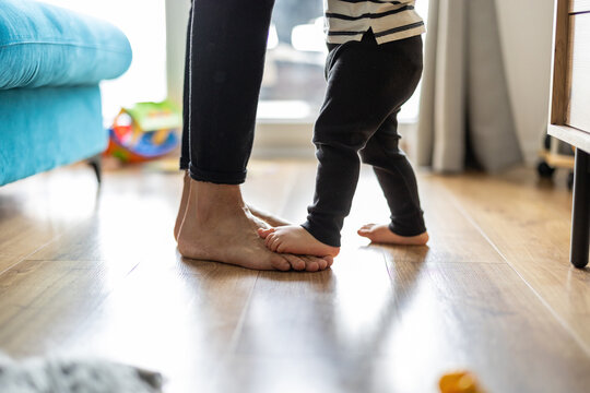 Baby son standing on mothers feet
