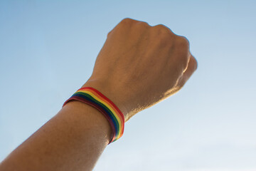 Close-up of a hand of an unrecognizable person with a multicolored armband with raised fist. Gay...