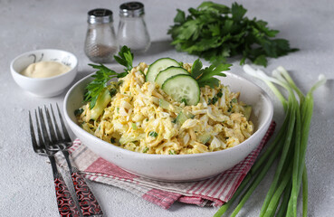 Salad with chicken, Chinese cabbage, cucumber, boiled eggs and cheese in white bowl on gray background
