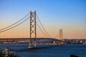 Towering suspension bridge over calm channel at sunset