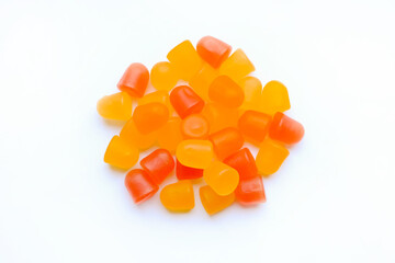Close-up texture of orange and yellow multivitamin gummies in the form of bears on white...