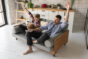 Handsome young father and his teenager son spending quality time together, watching sport game, football, hockey. Family time, having fun, enjoy. Fatherhood, parenting concept. Two generations