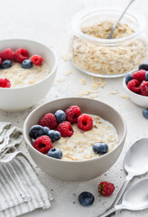 Milk oatmeal porridge with fresh betties  raspberries and blueberries. Healthy breakfast. Vegetarian food. Selective focus 