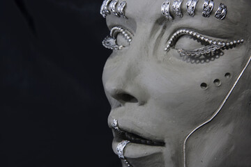 Female face profile. Clay sculpture and metal decoration on black background. Portrait in process of creation.