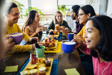 Happy group of multiracial friends having breakfast together and talking at coffee bar restaurant -...