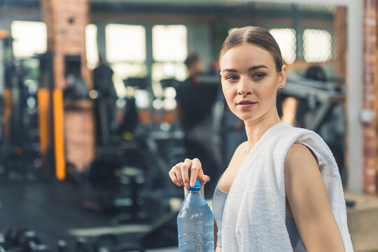 Closeup portrait of a caucasian millennial gorgeous girl opening a water bottle and relaxing after an exhausting exercising. High quality photo