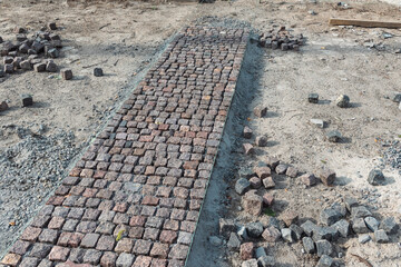 Stone pavement, construction worker laying cobblestone rocks on sand