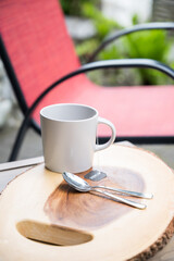 A mug of tea or coffee on a wooden log coffee outdoor patio table at a hotel or Air BnB unit.