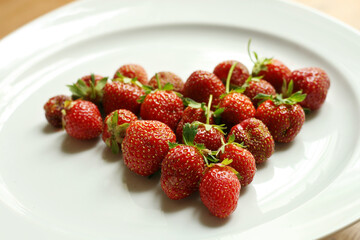 Heart made of strawberries. Fresh strawberries on the white plate arranged in the shape of heart. Fresh nice strawberries. Heap of Red strewberry on plate close up. Juice strawberry. 