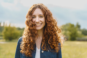 Spontaneous pretty young redhead woman smiling looking at the camera outdoors in the nature -...