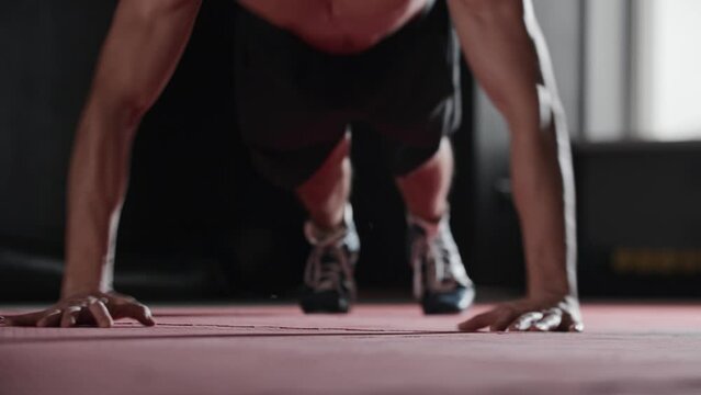 Athletic young man does low push ups with clapping his hands