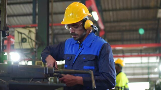 Professional industrial engineer, technician, factory worker wear hard hat, safety glasses. While checking, set up, control machine heavy industry factory. Employee working in manufacturing facility.