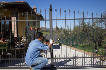 Picture of a handyman painting the driveway gate of the house
