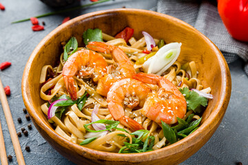 Udon noodles with shrimps on wooden bowl on grey table macro close up