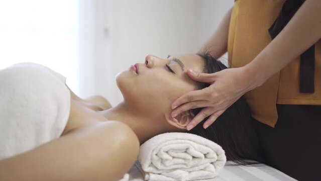Spa masseuses are massaging head or facial massage of Asian women.Woman is lying in the massage bed with comfort and relaxation and feels calm during the massage at luxury spa. Health care cocept.