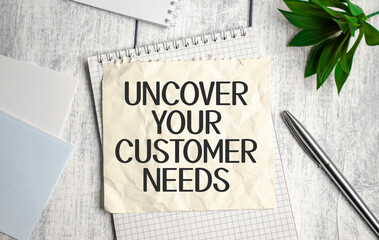 uncover your customer needs text on white notepad