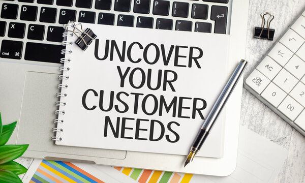 laptop charts, pen and a white notebook with the text uncover your customer needs