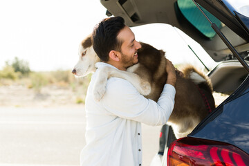 Smiling man taking out his dog during a car trip