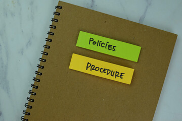 Concept of Policies and Procedure write on a book isolated on Wooden Table.