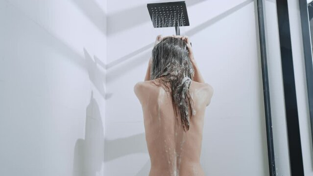 back view caucasian woman model take shower washing long hair with shampoo