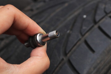 Male hand holding silver metal tubeless tire valve