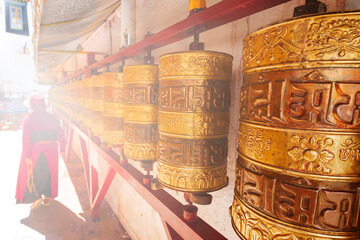 Tibetan pilgrim and Prayer wheels along a pilgrim route in Lhasa, Tibet