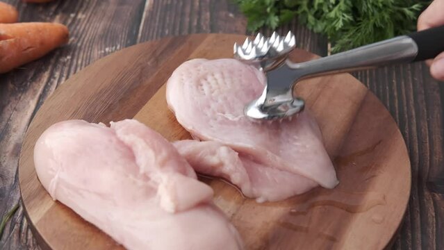 precessing raw chicken breast on a chopping board 