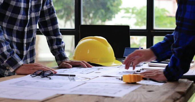 Two Civil Engineer or Architect holding helmet and handshaking after mega project done. handshake engineer sketching a construction project concept.4K side view.