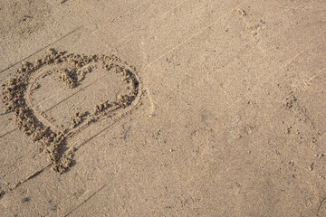 A heart drawn in the sand. Beach background. Top view, space for text