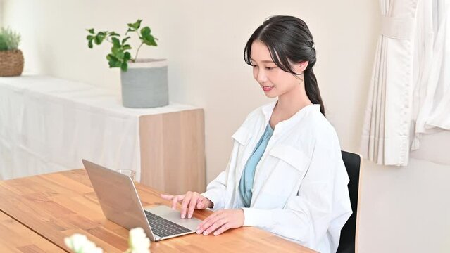 パソコンを使いながら仕事をする美しい若い日本人女性　左側にコピースペースあり