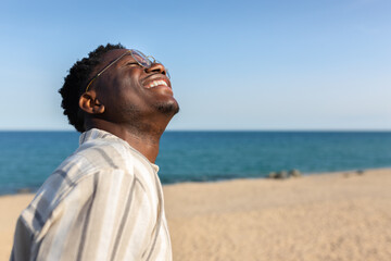 Happy young black man smiling. African american man enjoying holidays on the beach. Copy space.
