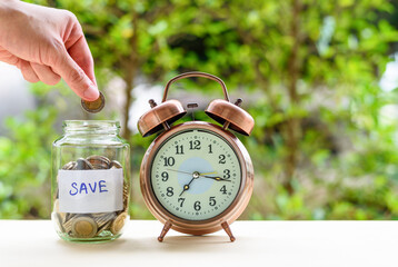 Saving money for sustainable life in the future concept : Hand drops a coin in a depositing jar for...