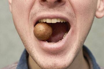 a man tries to crack a macadamia nut with his teeth