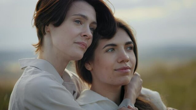 Two loving lesbians sitting closely and embracing outdoors