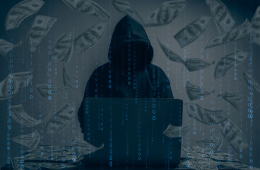 The hacker was wearing a black hoodie. Stealing huge financial data on computers with binary code digital interface and lots of falling dollars and lying on the table.Hacking and malware concept.