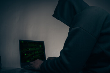 The hacker was wearing a black hoodie. Stealing huge financial data on computers with binary code digital interface.Hacking and malware concept.