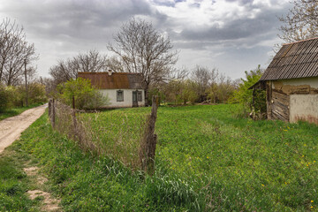Fototapeta na wymiar Summer village. A house in the village. A rustic abandoned house on a sunny day under a cloudy sky.