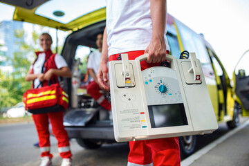 Hand of the doctor with defibrillator. Teams of the Emergency medical service are responding to an...