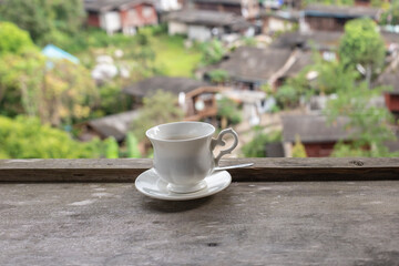 Cup of coffee on wooden table and blurred background.