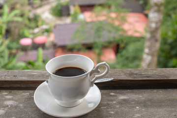 Cup of coffee on wooden table and blurred background.