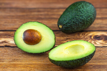 Halved avocado with seed on a wooden table.