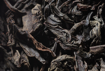 Dried black tea leaves as background.