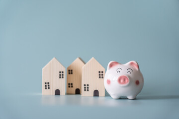 Piggy bank and small wooden house at back concept of savings. Save money to buy , loan , rent the...