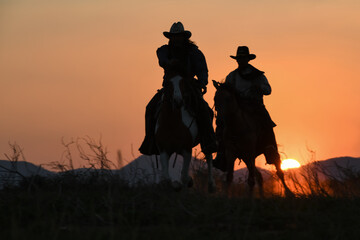 Vintage and shadow of a group of cowboys galloping on horseback at sunset.