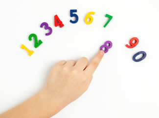 The child uses his index finger to move the number eight up. Early education. We learn colors and count from zero to ten