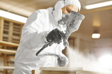 Man working with paint spray gun, airless spraying to wood - obrazy, fototapety, plakaty